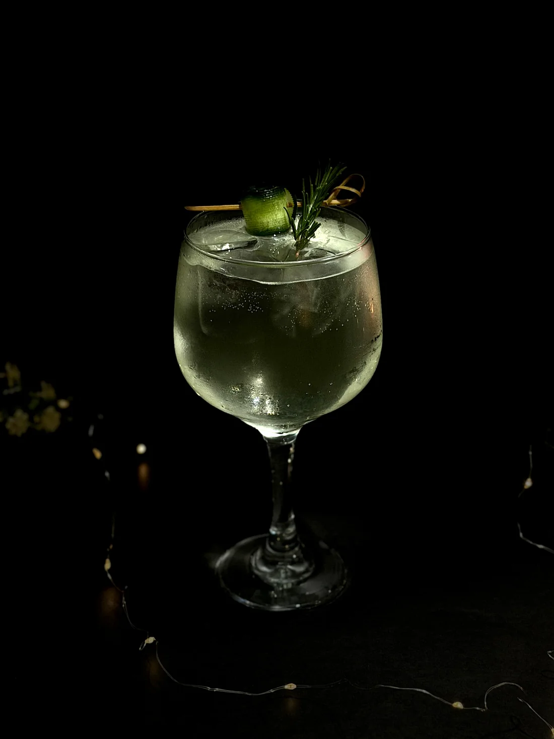 Cóctel transparente decorado con pepino y romero
